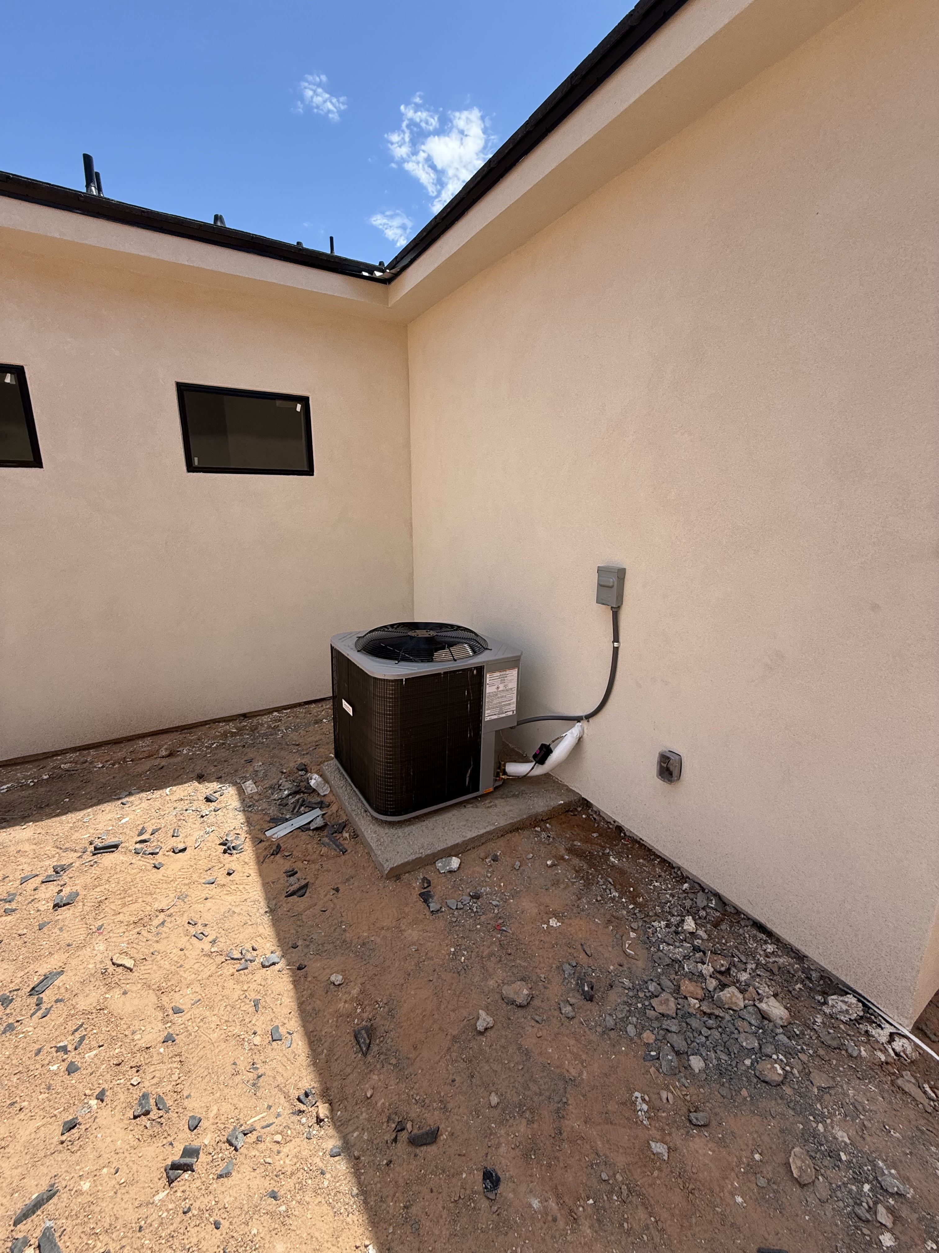 Outdoor air conditioning condenser beside a stucco home